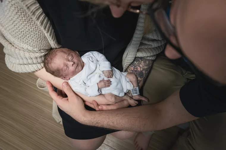 Mama en papa houden Senne samen in hun armen.